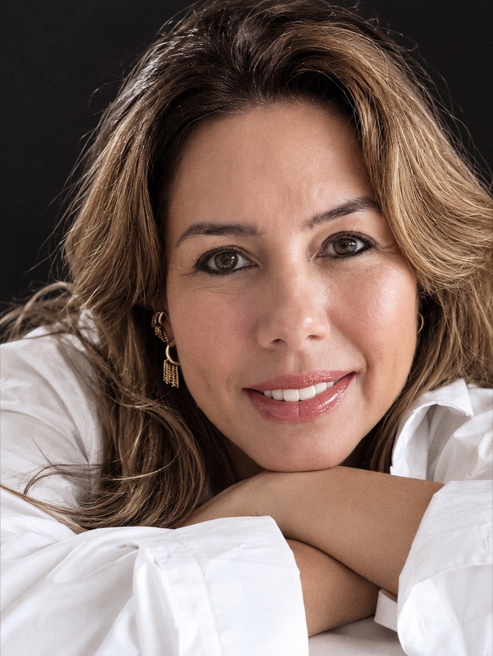 Viviane Canziani sorrindo, de camisa branca, com os braços cruzados à frente